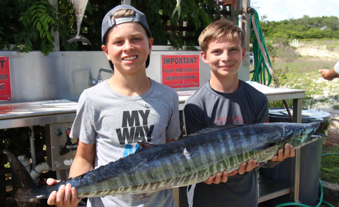 two boys with a large fish at legacy boating club