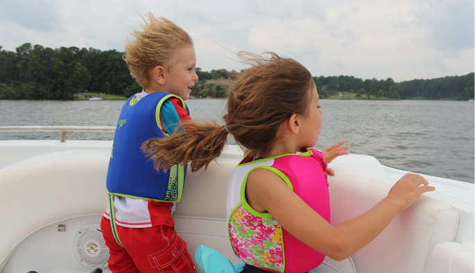 Two little kids on the front of a boat looking out at the ocean in Destin, Florida