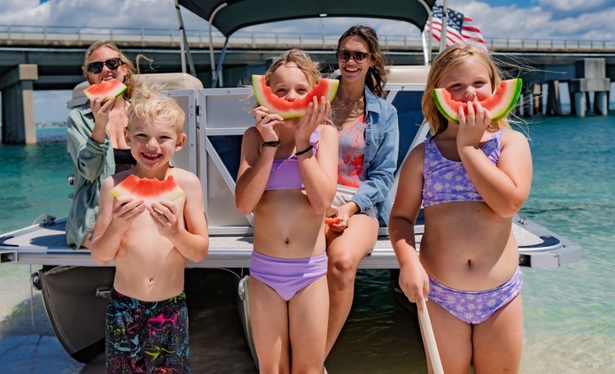 family on the beach in destin fl eating melon