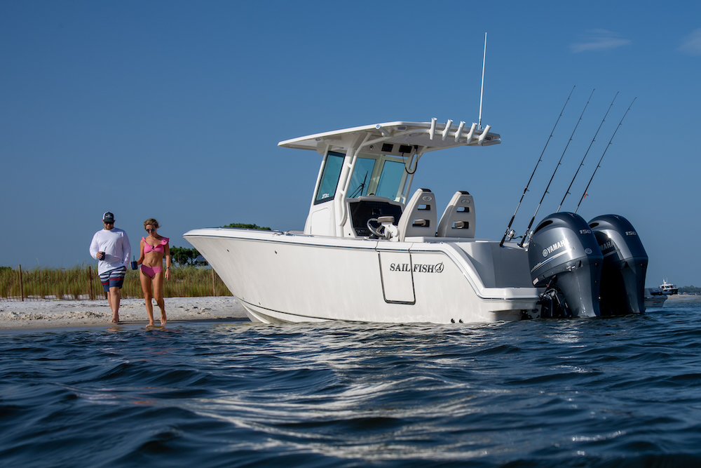couple relaxing beachside next to their parked sailfish twins deep sea fishing boat