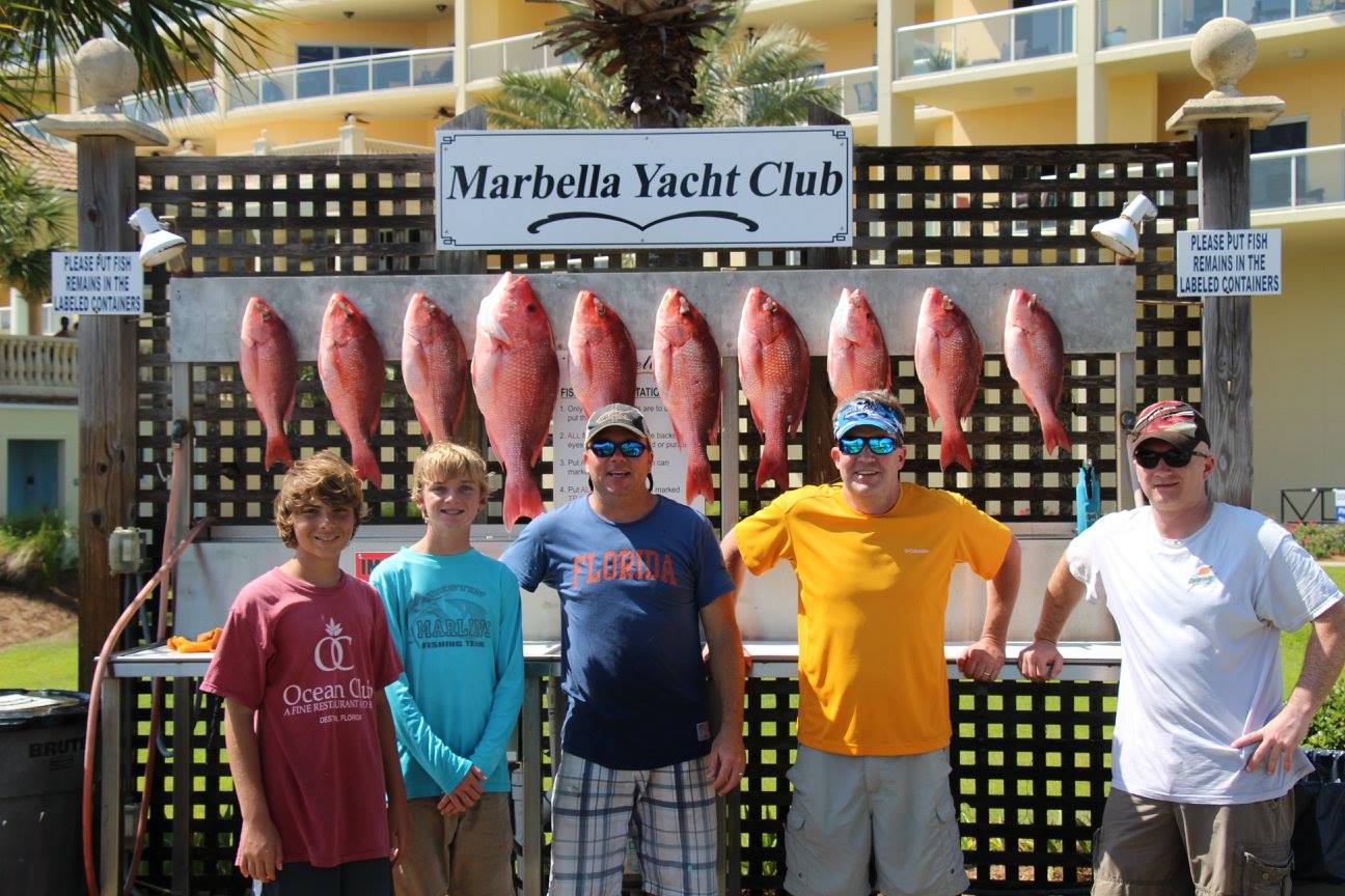 A group of people smiling in front of fish at the Marbella Yacht Club in Destin, Florida