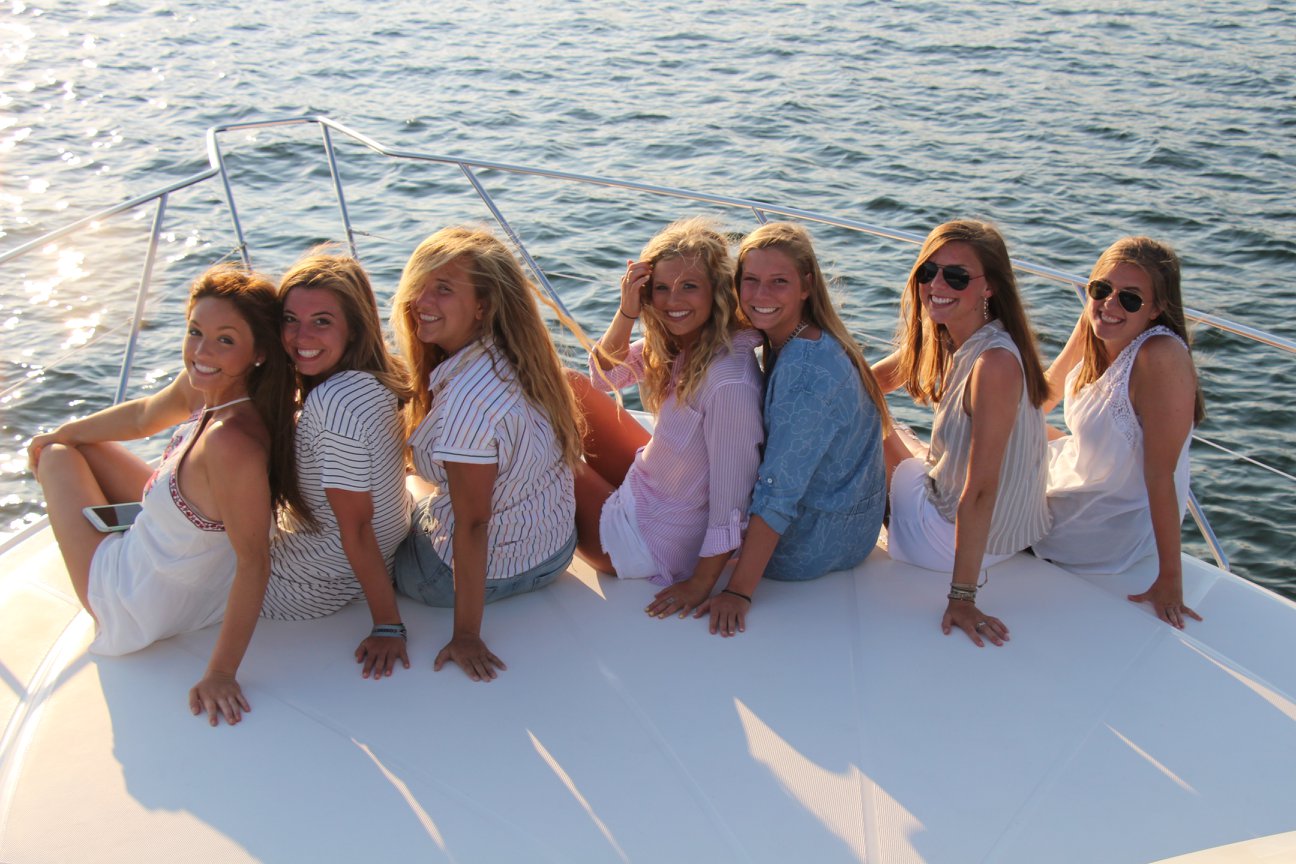 A group of 7 girls smiling on the back of a boat at sunset in Destin, Florida