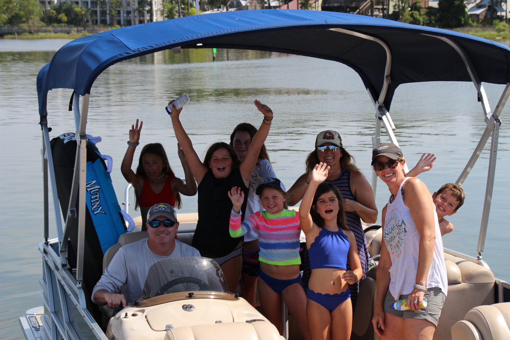 Family on a Tritoon boat in Destin, Florida raising their hands up in the air