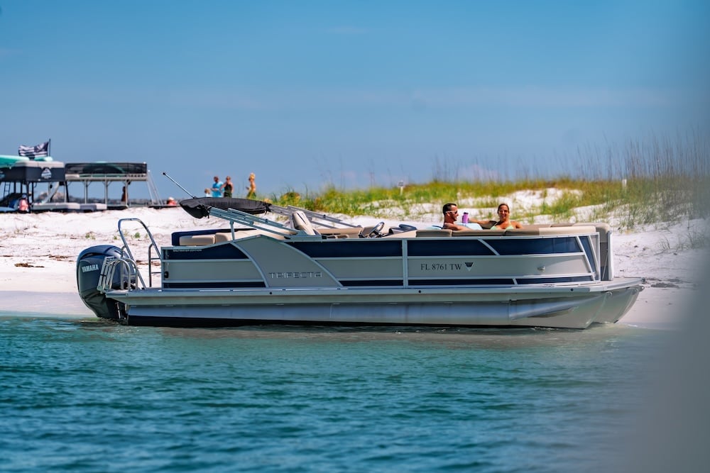 beached tritoon boat in dest with bimini top down