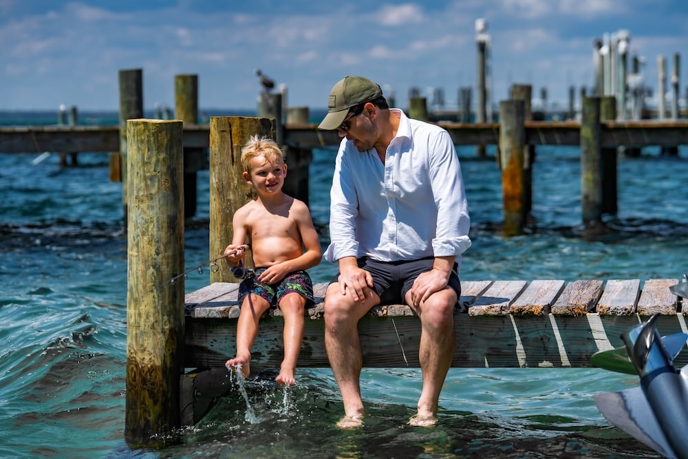 dad and son fishing off of a dock in the destin harbor near crab island