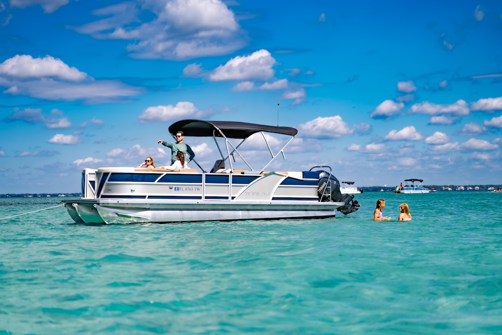 legacy tritoon boat anchored at crab island with family onboard and swimming nearby
