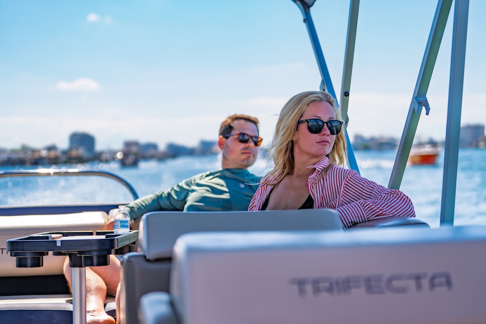 man and woman relaxing and looking toward shore aboard tritoon boat in destin fl