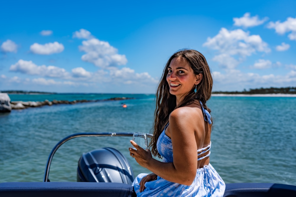 woman on the stern of tritoon relaxing and smiling at shell island pcb