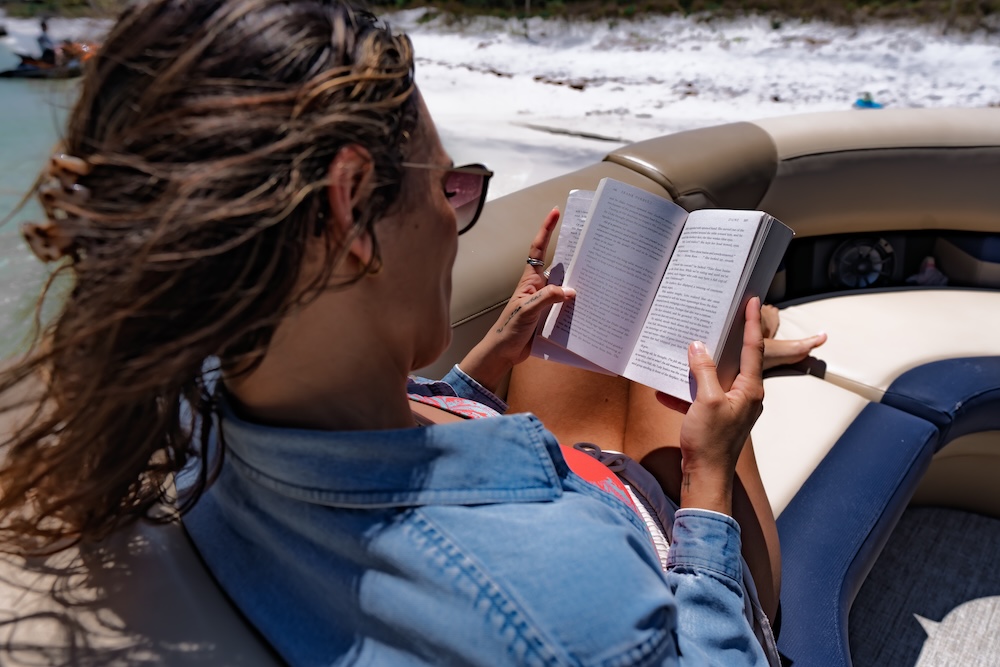 woman reading book on beached tritoon in destin fl
